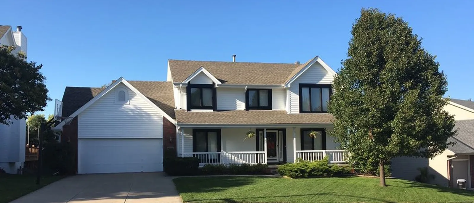 Completed siding replacement — crisp white lap siding with dark window trim